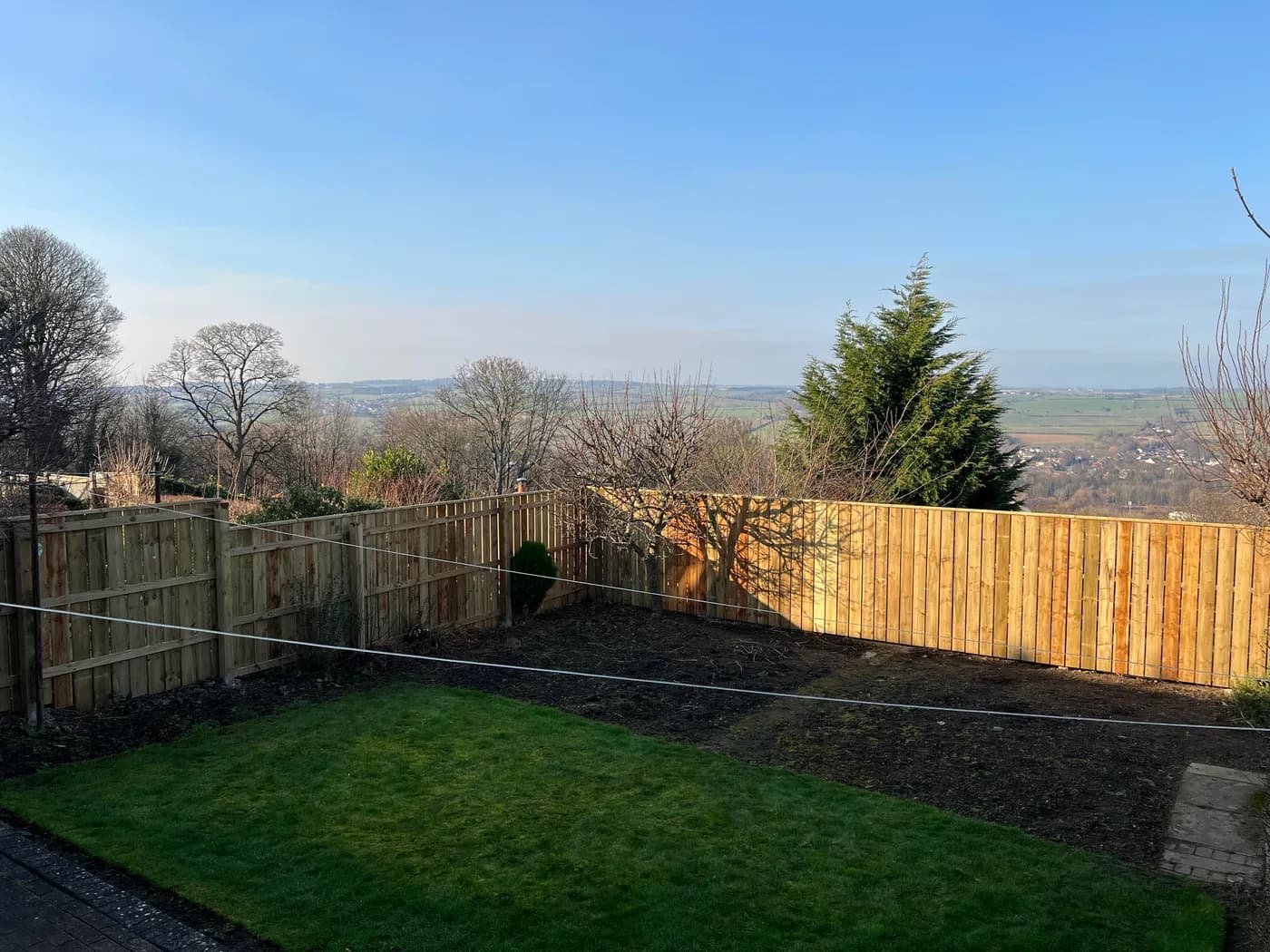 A newly installed timber fence enclosing a garden with a countryside view